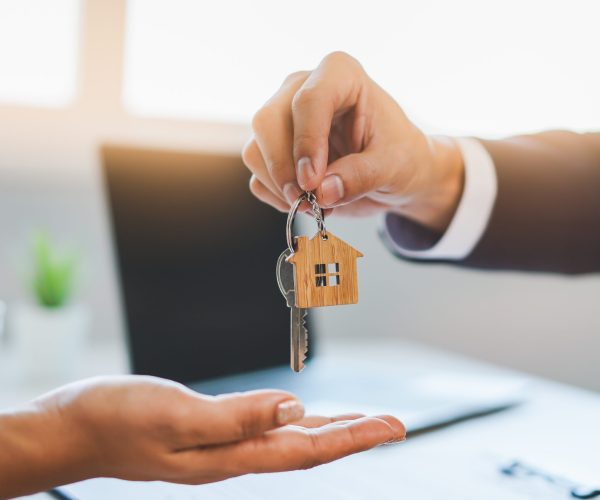 close up view hand of property realtor / landlord giving key house to buyer / tenant.